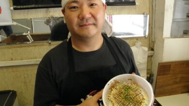 自慢のお好み焼きを手に店主の簗瀬さん