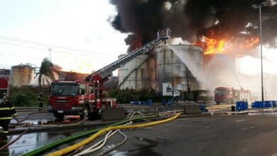 黒煙を上げて燃える燃料タンクと消火作業中の消防車（Corpo de Bombeiros da PMESP）