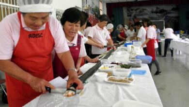 「思いは一つの絆寿司」。巨大な巻き寿司を切り分ける婦人ら