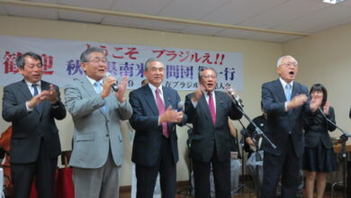 堀井副知事（右）ら南米訪問団全員が登壇し、歓迎会に参加した全員と秋田民謡「ドンパン節」を歌っている様子